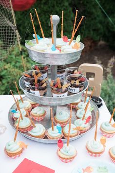 cupcakes are arranged on three tiered trays with toothpicks sticking out of them