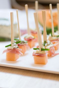 small appetizers with toothpicks are arranged on a white plate