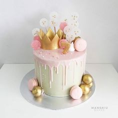 a pink and white cake with gold decorations on it's top, sitting on a table