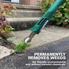 a green lawn mower sitting on the side of a sidewalk