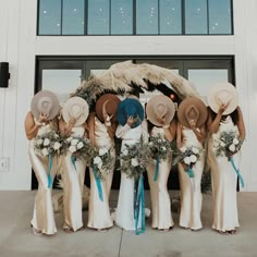 a group of women standing next to each other in front of a building with hats on their heads