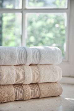 towels stacked on top of each other in front of a window