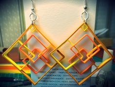 a pair of yellow and orange earrings hanging from a hook