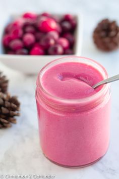 a glass jar filled with pink smoothie next to pine cones