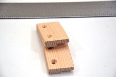 two wooden pegs sitting on top of a white table next to a ruler and a piece of wood