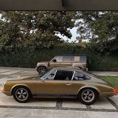 an old porsche parked in a driveway next to two suvs on the other side