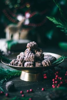 a pile of cookies sitting on top of a gold plate next to christmas decorations and greenery