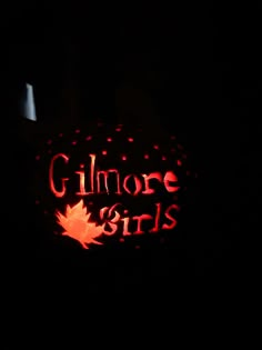 a carved pumpkin with the words, glimmore girls on it in red light