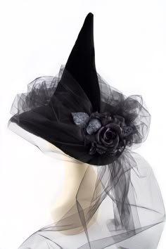 a white mannequin head wearing a black hat with a rose on it's side