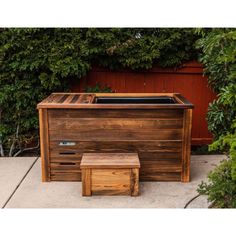 a wooden bench and stool in front of some bushes