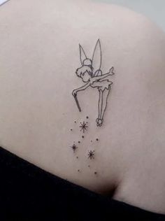 the back of a woman's shoulder with a small fairy tattoo on her left side