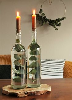 two wine bottles with plants in them sitting on a wooden table next to each other