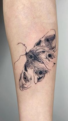 a black and white photo of a butterfly tattoo on the right calf's leg