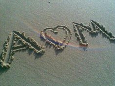 the word love spelled out in the sand with a rainbow painted on it's side