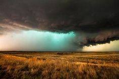 an image of a storm coming in from the sky over a grassy field with tall grass