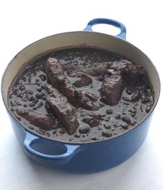 a blue pot filled with meat and beans