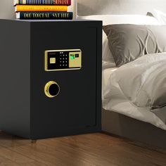 a black safe sitting on top of a wooden floor next to a pile of books