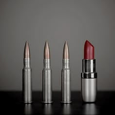 three lipsticks are lined up on a table with one red and the other silver