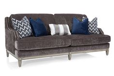 a gray couch with blue and white pillows on it's back end, sitting in front of a white background