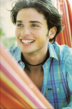 a man smiling while sitting in a hammock with his hands on his hips