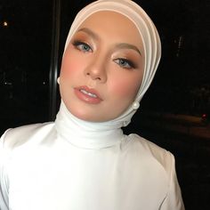 a woman wearing a white hijab is posing for the camera