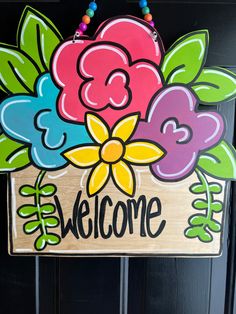 a welcome sign with flowers painted on it and beads hanging from the front door handle