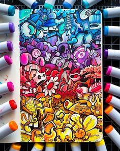 a notebook covered in lots of different colored crayons next to some pens and markers