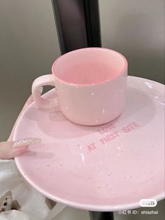 a pink coffee cup sitting on top of a white plate