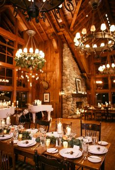 a dining room filled with lots of tables covered in white plates and place settings, surrounded by chandeliers