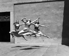 black and white photograph of three women jumping in the air with their legs spread out