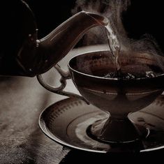 tea being poured into a cup on top of a saucer