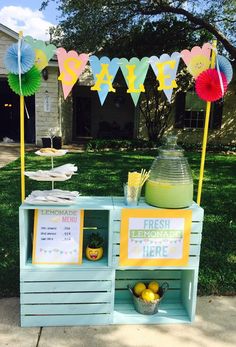 an ice cream stand with lemons and paper fans on it's top, in front of a house