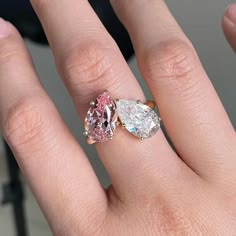 a woman's hand with a pink and white diamond ring on top of it