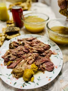 a white plate topped with meat and veggies next to bowls of sauces