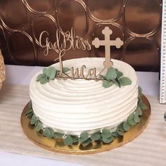 a white cake with green leaves and a cross on top that says godless luna