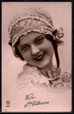 an old photo of a woman with a hat on her head and smiling at the camera