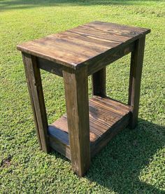 a small wooden table sitting on top of a lush green grass covered field next to a tree