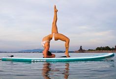 a woman is doing yoga on a surfboard in the water with her legs up