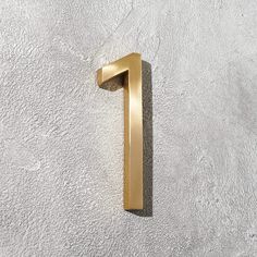 the number one is shown in gold on a white wall with grey concrete flooring