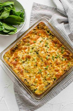 a casserole dish with spinach and cheese in it next to a bowl of greens