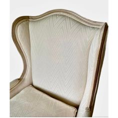 an upholstered chair with white fabric and wood trimmings on the back