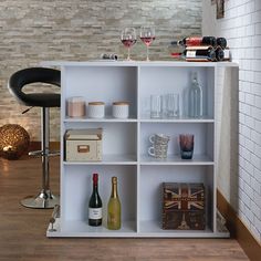 a white shelf with bottles and glasses on top of it next to a bar stool