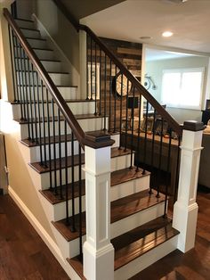 there is a stair case in the middle of this living room with wood floors and white railings