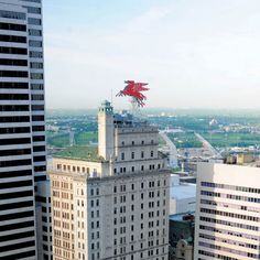 two tall buildings with a red dragon on top in front of a cityscape