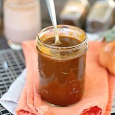 a glass jar filled with brown liquid sitting on top of a pink napkin next to an orange towel