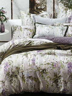 the comforter is made up with flowers on it and has purple, green, and white colors