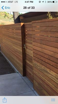 a wooden fence that is next to a sidewalk and some bushes on the side of it