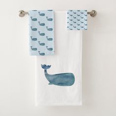 two towels hanging on the side of a towel rack, one with a whale design