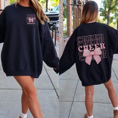 Get ready to cheer in style with our "Cheer" Sweatshirt featuring a Coquette Bow! 📣🎀 This trendy and comfortable sweatshirt is perfect for every cheerleader who loves to add a touch of elegance to their cheer gear. Featuring the word "Cheer" alongside an adorable coquette bow, this sweatshirt is the ultimate way to showcase your passion for cheerleading with a fashionable twist. 🎨 Vibrant and Trendy Colors: Available in a variety of fashionable colors, this sweatshirt is designed to match you Cheer Team Sweatshirts, Casual Tops For Cheerleading In Fall, Fall Cheerleading Crew Neck Sweatshirt, Varsity Sweatshirt For Cheerleading In Fall, Fall Crew Neck Sweatshirt For Cheerleading, Black Long Sleeve Cheerleading Sweatshirt, Black School Spirit Sweatshirt For Cheerleading, Cheerleading Tops For Fall, Winter Crew Neck Sweatshirt For Cheerleading