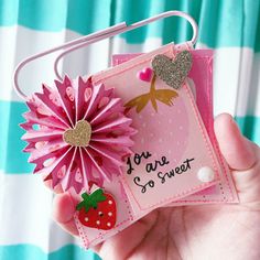 a hand holding a card with a pink flower and a strawberry on it, that says you are so sweet